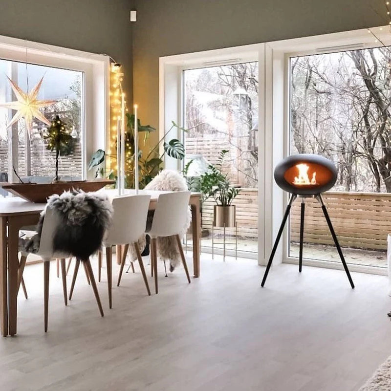 Rustic Flame Tripod Ethanol Fireplace providing cozy warmth in a modern dining room setting.