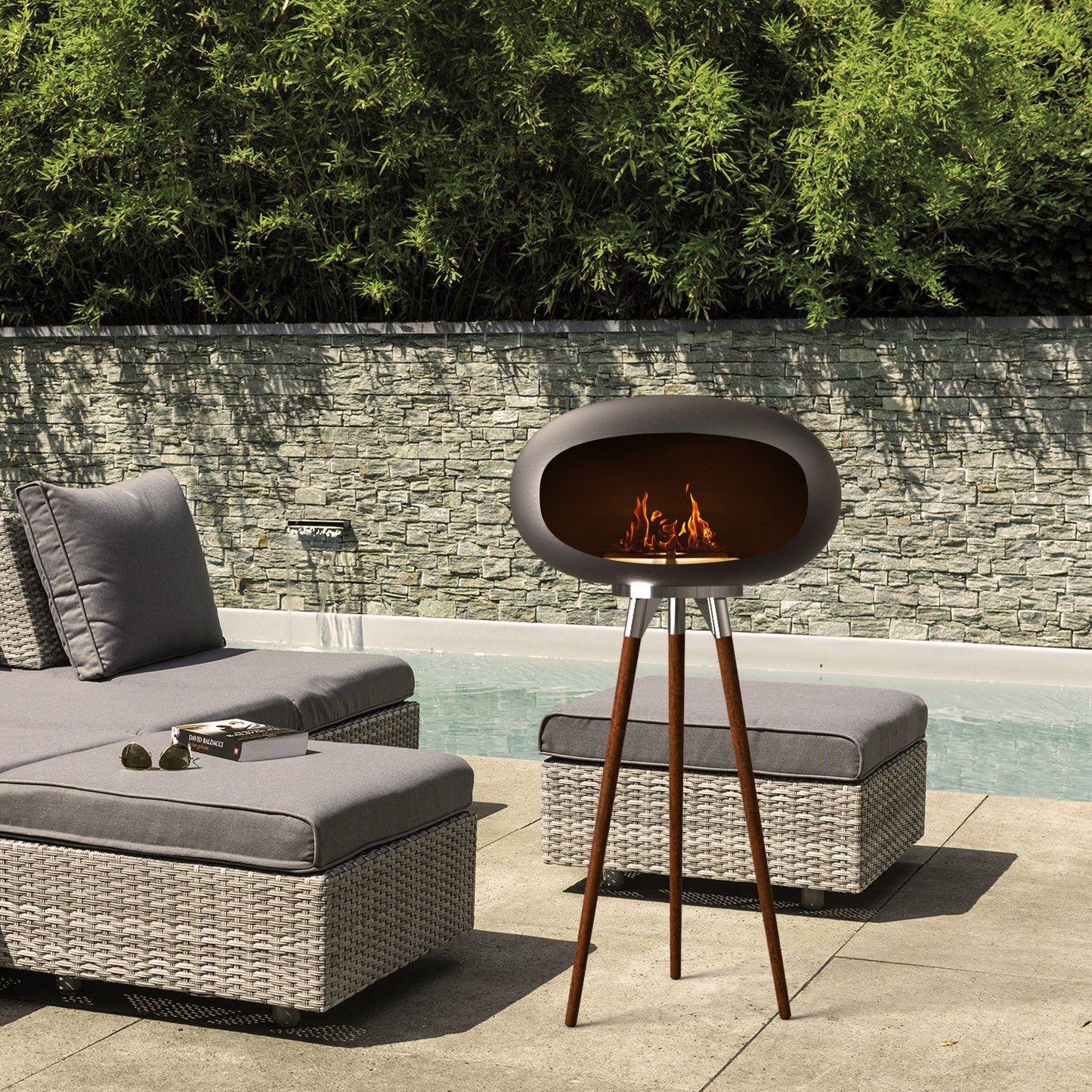 Tripod Ethanol Fireplace adding a warm, smokeless glow to an outdoor patio gathering next to a pool.