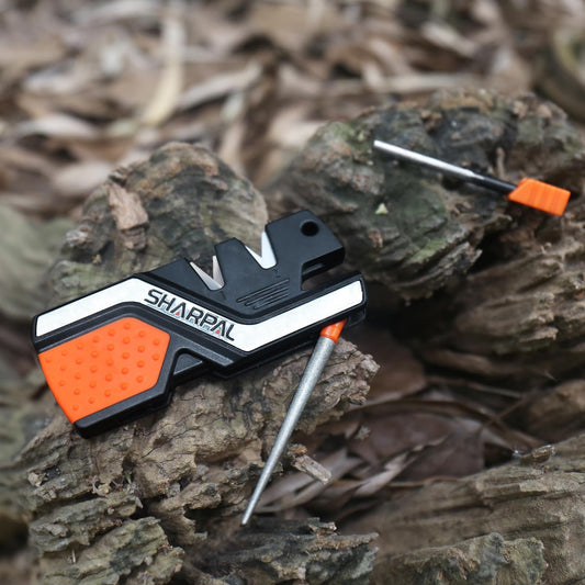 6-in-1 Pocket Knife Sharpener & Survival Tool with Fire Starter, on log.